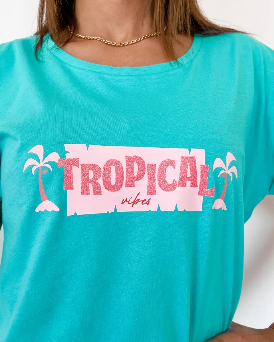 TROPICALのロゴをグリッターシートで圧着したターコイズのTシャツを着た人